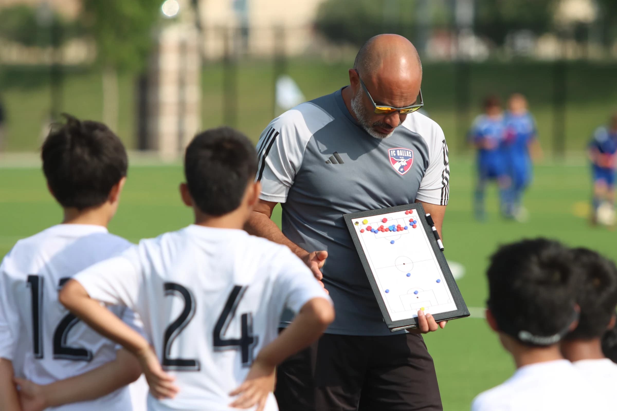 Coach Alberto Carbajal explaining tactics to young footballers using a coaching board