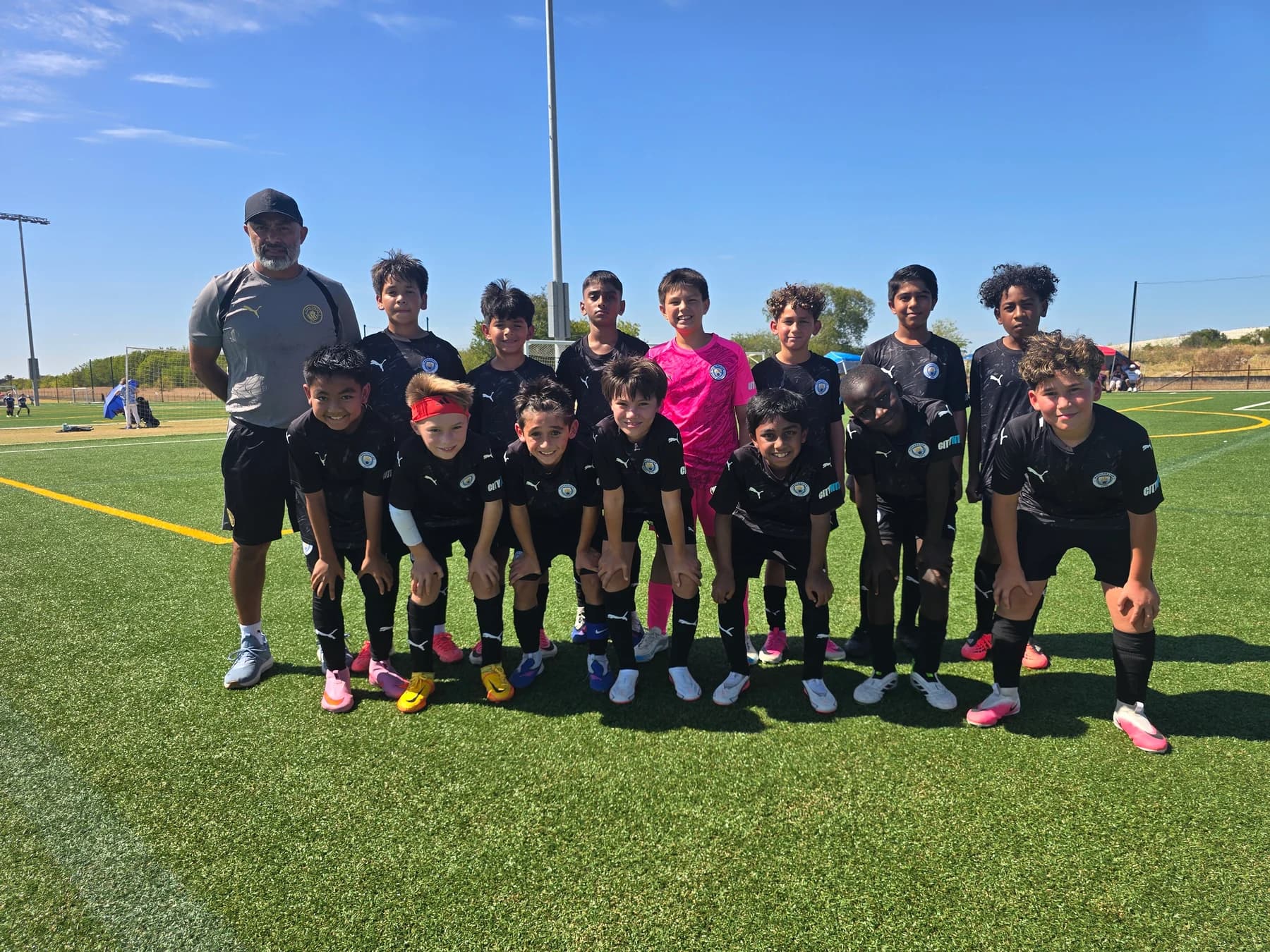 Coach Alberto Carbajal and his Manchester City North Texas FC U11 team together on the football pitch