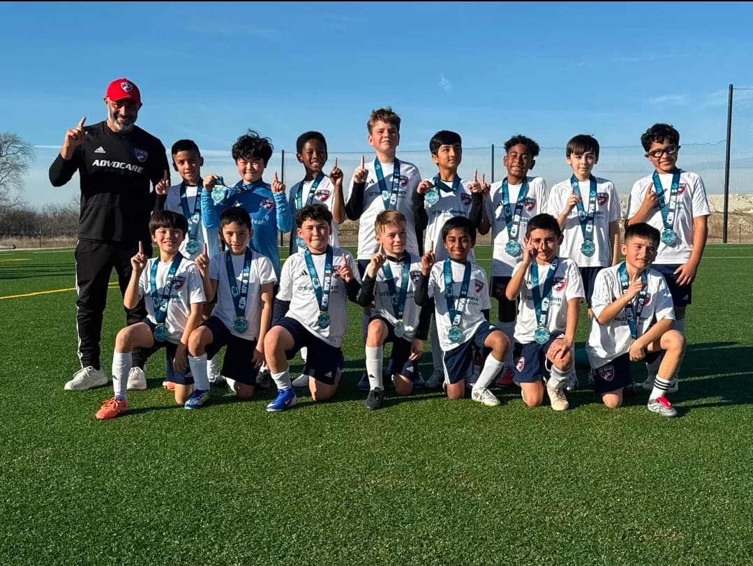 Alberto Carbajal and the FC Dallas 2016 Boys team together on the pitch wearing medals